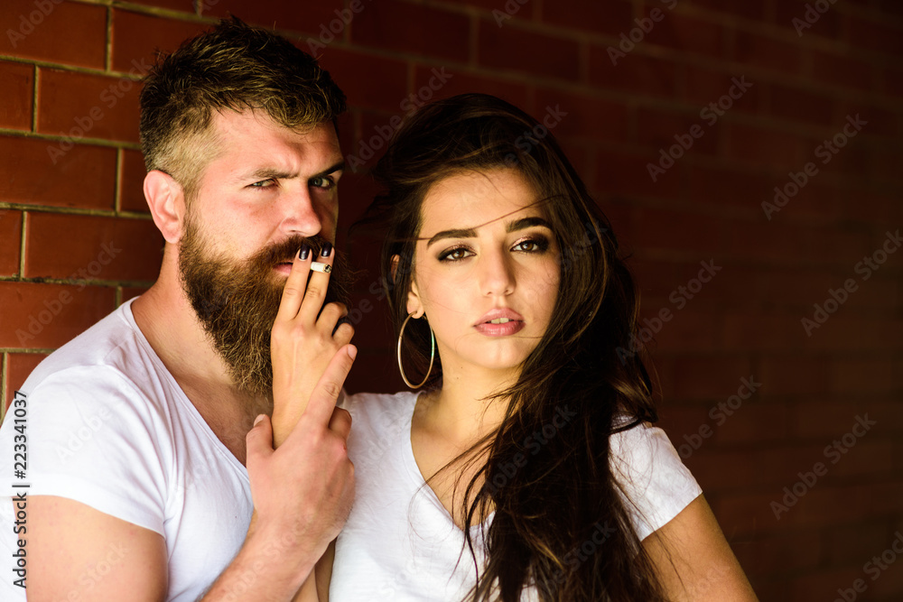 Couple in love hugs while smoking cigarette brick wall background. Break or pause for smoking. Share single cigarette. Couple find place to hide from witnesses, smoking cigarette in tranquility Couple in love hugs while smoking cigarette brick wall background. Break or pause for smoking. Share single cigarette. Couple find place to hide from witnesses, smoking cigarette in tranquility