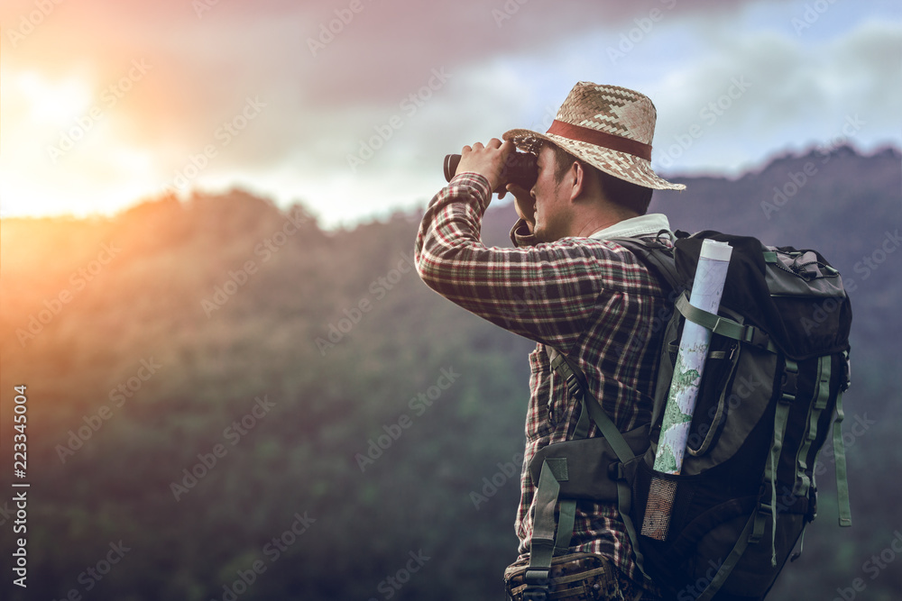 hiker with backpack standing looking through binoculars on the mountain - obrazy, fototapety, plakaty 