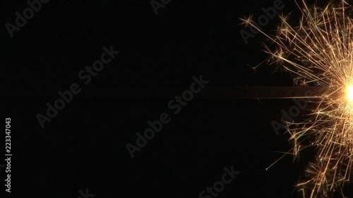 Close up of a single sparkler burning horizontally through the middel of the frame. photo