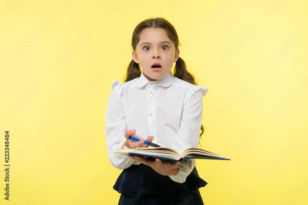 Girl cute schoolgirl in uniform hold book with information yellow background. Pupil get information from book. Child wear school uniform prepare for lesson information. Surprised about information