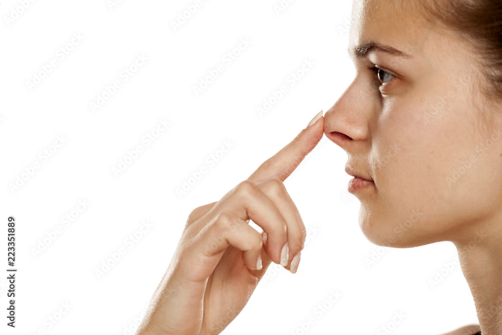 Profile of young woman touching her nose on white background Profile of young woman touching her nose on white background