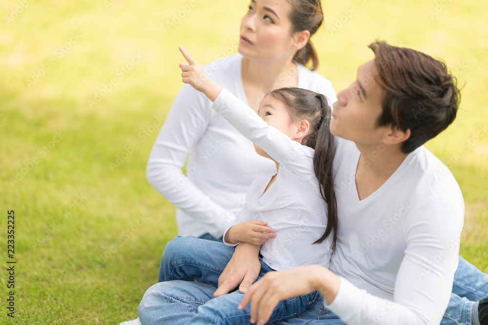 Family sitting on grass together.Young parent with little girl have playing for fun in nature outside.