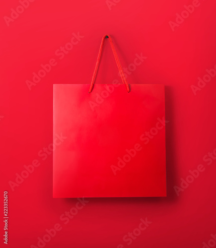 Mockup of red paper shopping bag with handles on the red color background photo