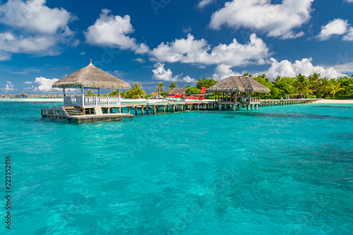 Maldives island beach. Wooden jetty, seaplane and exotic tropical island, view from amazing blue sea