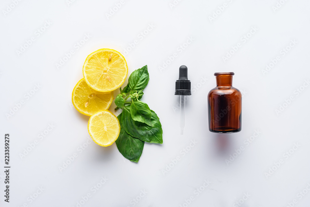 top view of bottle of natural herbal essential oil, dropper, lemon pieces and green leaves isolated on white top view of bottle of natural herbal essential oil, dropper, lemon pieces and green leaves isolated on white