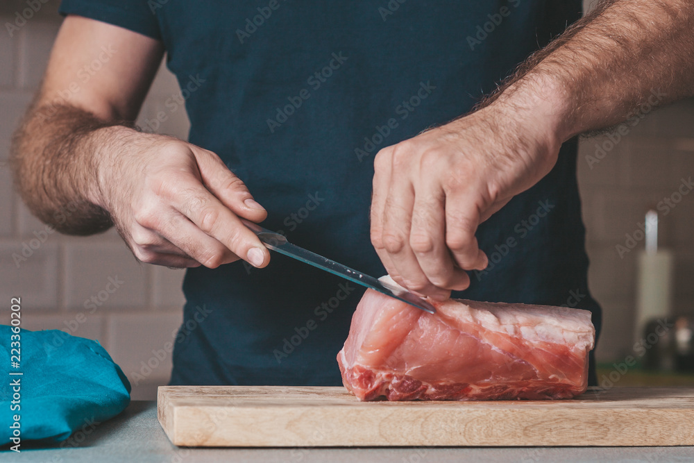 The cook cuts a large piece of pork