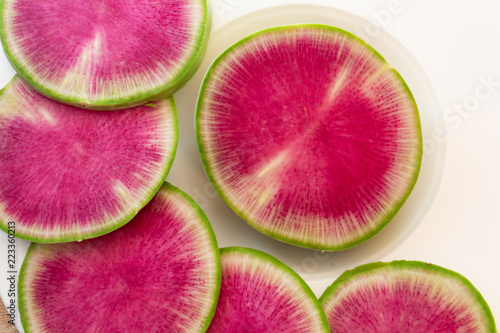 Close view of watermelon radish slices on a white plate, horizontal aspect