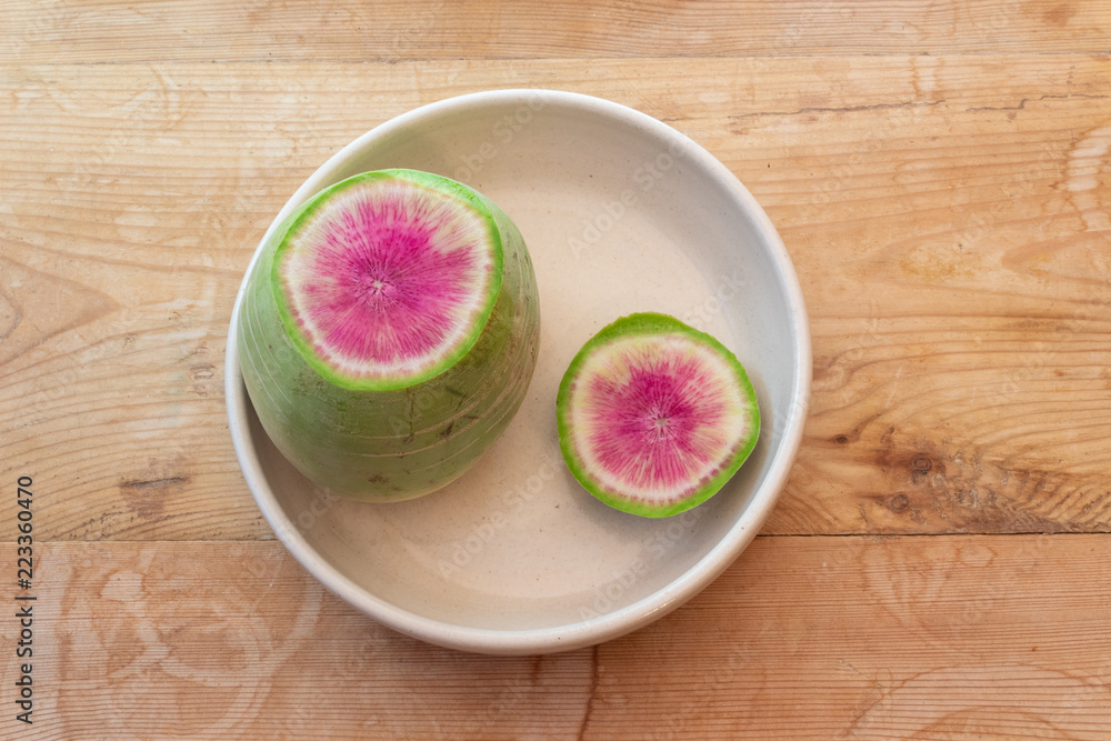 Sliced open watermelon radish in a white bowl on an old wooden table, horizontal aspect Sliced open watermelon radish in a white bowl on an old wooden table, horizontal aspect