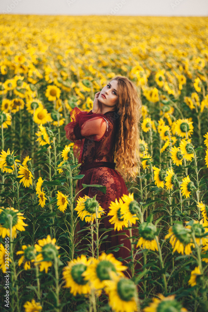 Young beautiful woman in a dress among blooming sunflowers. Agro-culture. Young beautiful woman in a dress among blooming sunflowers. Agro-culture.