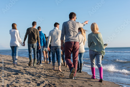 Group of friends running on beach during autumn day