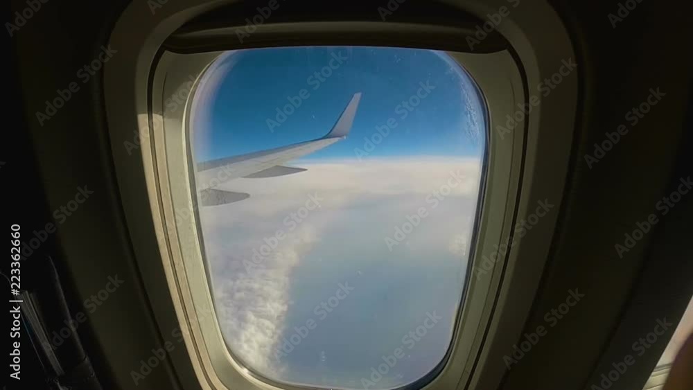 aircraft flies over the clouds, view through the window to the wing of an passenger airplane aircraft flies over the clouds, view through the window to the wing of an passenger airplane