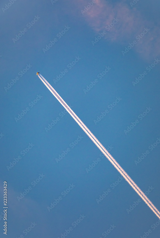Fototapeta premium aircraft with contrail in morning sun