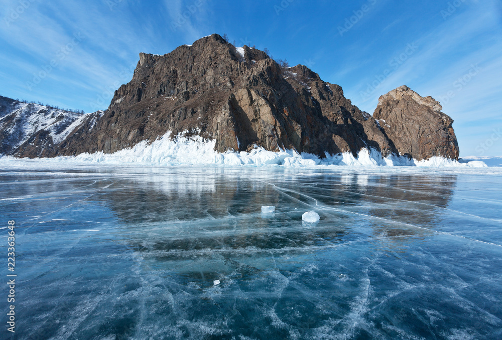 Lake Baikal. A view from the blue ice to the northern rocky tip of Olkhon Island and Cape Khoboy or Virgin Rock (Skala Deva) on a sunny winter day