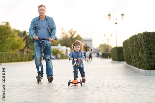 the father walks with the child, ride scooters and Having Fun outdoors