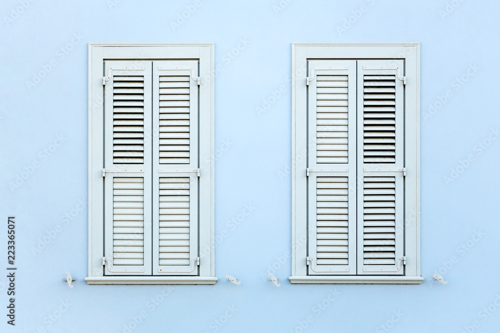 Two wooden retro style windows with shutters, on clean painted wall. Two wooden retro style windows with shutters, on clean painted wall.