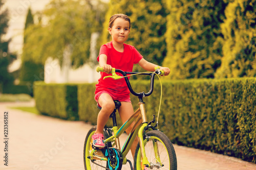 Child riding bike. Kid on bicycle in sunny park. Little girl enjoying bike ride her way to school warm summer day. Preschooler learning to balance bicycle Sport for kids.