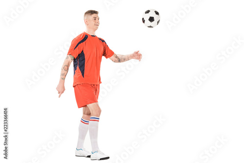 Fototapeta Naklejka Na Ścianę i Meble -  full length view of smiling young soccer player kicking ball isolated on white