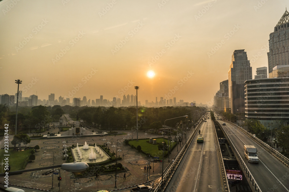 Sunrise Above The Bangkok City Skyline. High Buildings Behind a Park with Highway on Foreground