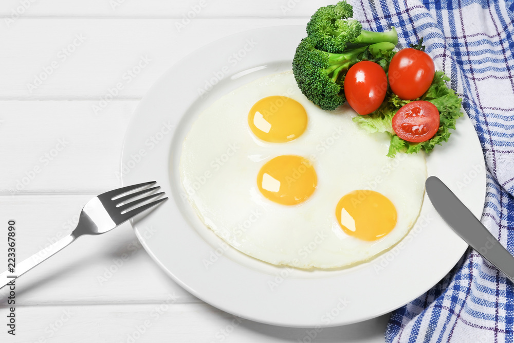 Fried eggs with vegetables on the wooden table Fried eggs with vegetables on the wooden table