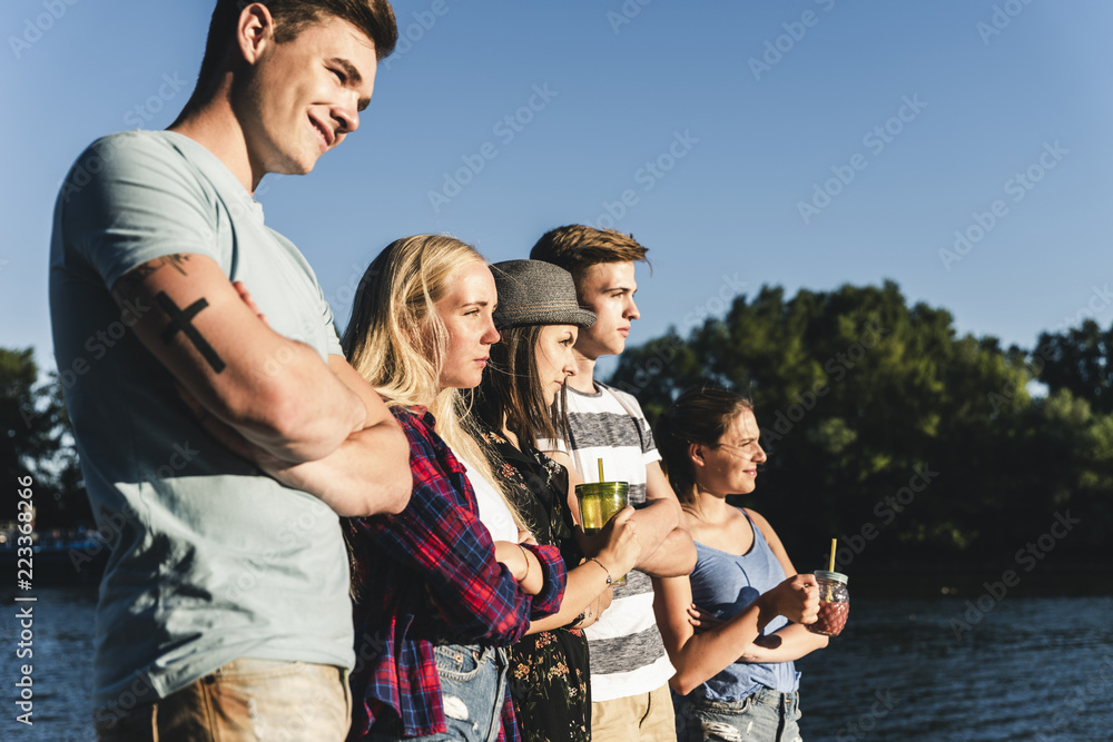 Group of friends standing at the water looking out Group of friends standing at the water looking out