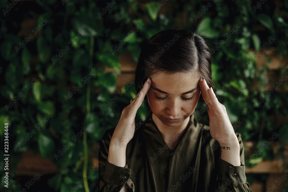 Focused young woman at wall with climbing plants Focused young woman at wall with climbing plants