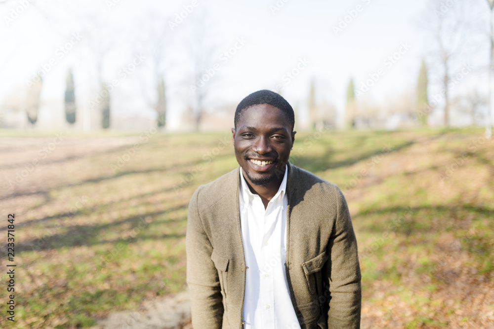 Portrait of young man in park, wearing jacket, smiling Portrait of young man in park, wearing jacket, smiling