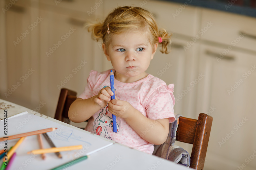 Cute adorable baby girl learning painting with pencils. Little toddler child drawing at home, using colorful felt tip pens. Healthy happy daughter experimenting with colors at home or nursery. Cute adorable baby girl learning painting with pencils. Little toddler child drawing at home, using colorful felt tip pens. Healthy happy daughter experimenting with colors at home or nursery.