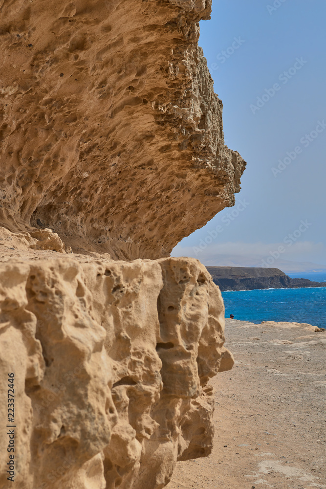 Rocky limestone formation in the village of Ajuy with black stone cliff and volcanic background the calm blue sea and clear sky.in Fuerteventura, Canary Islands, Spain