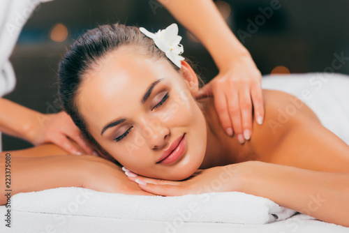 attractive young woman having massage and relaxing at massage salon