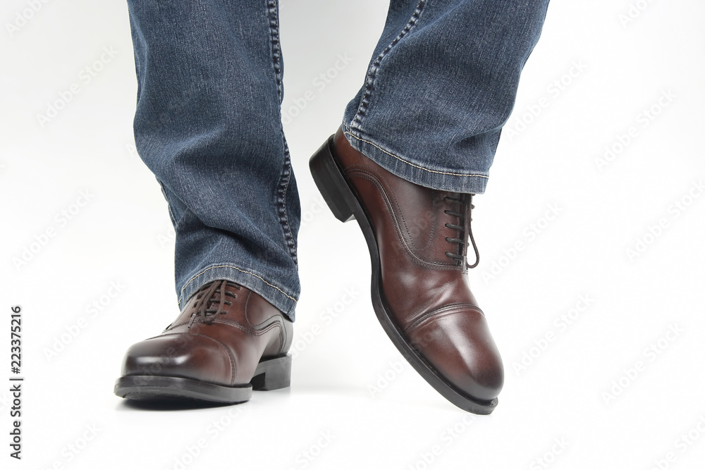 Men's legs in jeans shod in classic brown Oxford shoes Men's legs in jeans shod in classic brown Oxford shoes