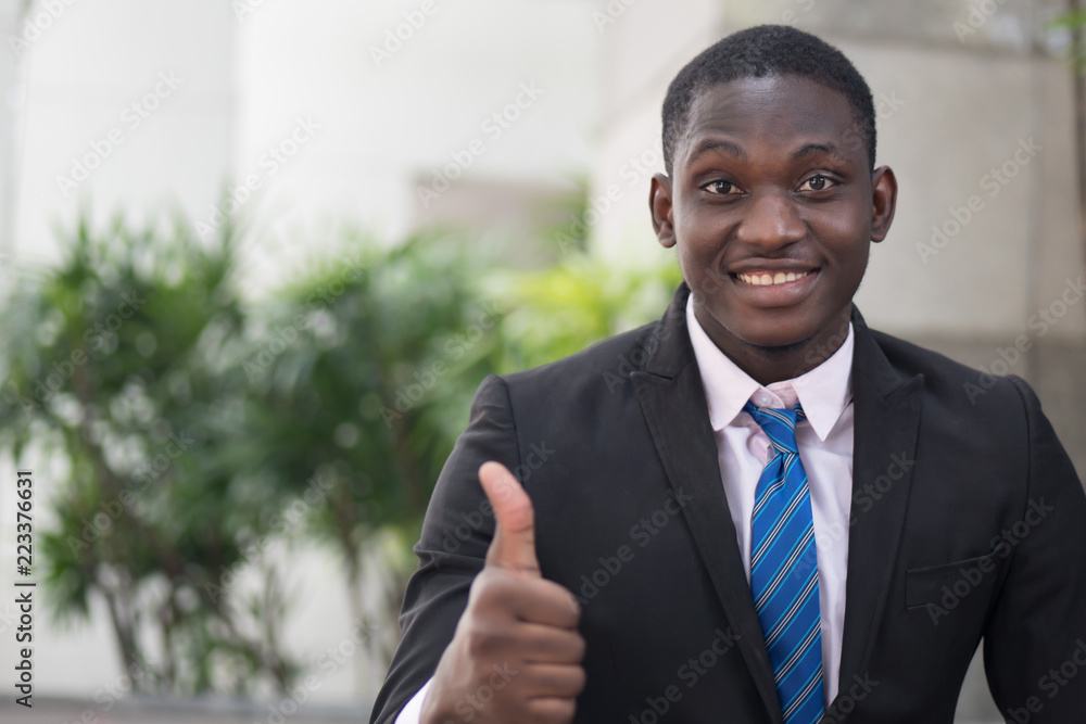 african businessman giving thumb up; portrait of successful confident african business man showing success thumb up gesture for winner, successful business deal; young adult african man model african businessman giving thumb up; portrait of successful confident african business man showing success thumb up gesture for winner, successful business deal; young adult african man model