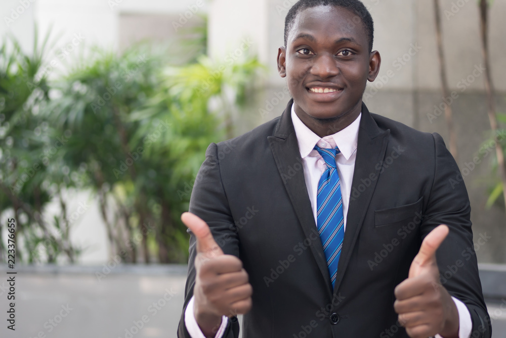 african businessman giving thumb up; portrait of successful confident african business man showing success thumb up gesture for winner, successful business deal; young adult african man model african businessman giving thumb up; portrait of successful confident african business man showing success thumb up gesture for winner, successful business deal; young adult african man model
