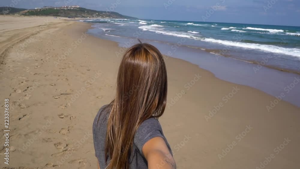 young woman pulling her boy friend in shorts at a windy beach towards the sea in slow motion x4 young woman pulling her boy friend in shorts at a windy beach towards the sea in slow motion x4
