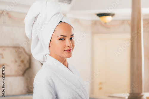 young woman in bathrobe with towel on head at spa salon