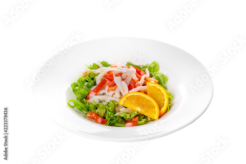 Salad with seafood with squid, tomato, bell pepper, fish, salmon, lettuce and orange, citrus on plate, white isolated background Side view. For the menu, restaurant, bar, cafe