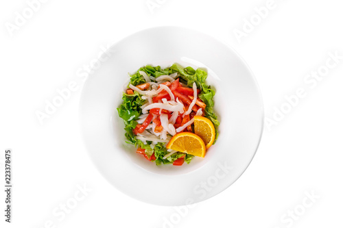 Salad with seafood with squid, tomato, bell pepper, fish, salmon, lettuce and orange, citrus on plate, white isolated background, view from above, for the menu, restaurant, bar cafe