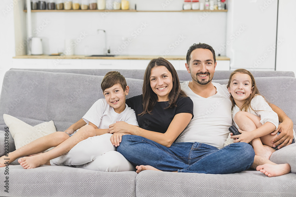 Happy family of four sitting on sofa. Happy family. Father, mother and children at home Happy family of four sitting on sofa. Happy family. Father, mother and children at home