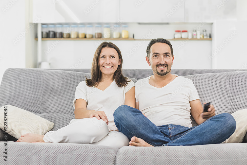 Smiling young couple relaxing and watching TV at home Smiling young couple relaxing and watching TV at home
