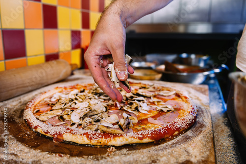 Putting Mushrooms On Pizza In Pizza Restaurant photo