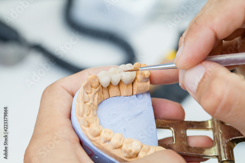 dental technician works by brush with jaw model photo