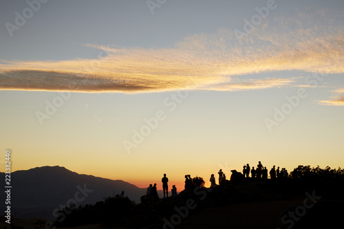 Silhouette of Large Crowd of Tourists on a Mountain Top at Sunset