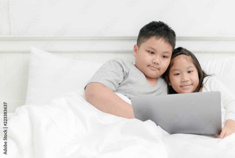 Brother and sister play laptop on bed together Brother and sister play laptop on bed together