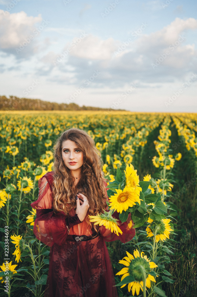 Young beautiful woman in a dress among blooming sunflowers. Agro-culture. Young beautiful woman in a dress among blooming sunflowers. Agro-culture.