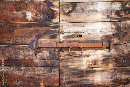 Antico catenaccio chiavistello arrugginito  su un  vecchio portone in legno  photo