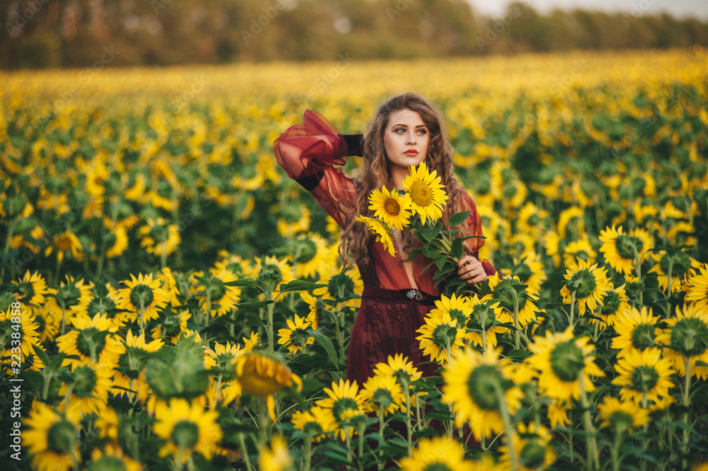 Young beautiful woman in a dress among blooming sunflowers. Agro-culture. Young beautiful woman in a dress among blooming sunflowers. Agro-culture.
