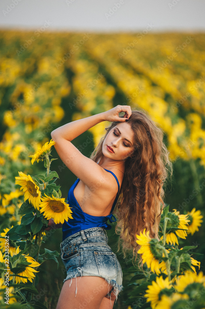 Young beautiful woman in a dress among blooming sunflowers. Agro-culture. Young beautiful woman in a dress among blooming sunflowers. Agro-culture.