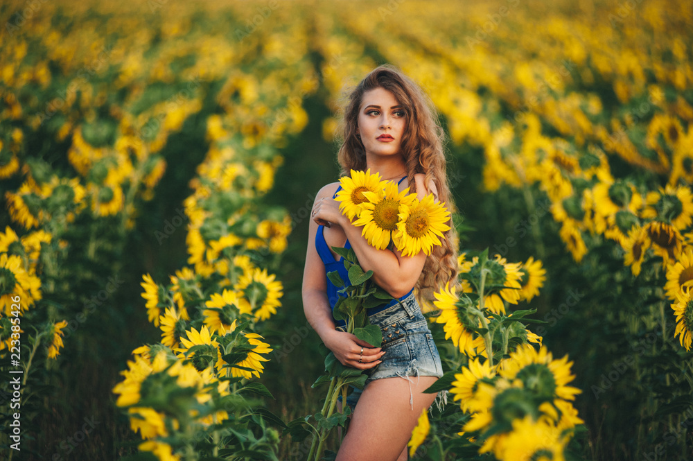 Young beautiful woman in a dress among blooming sunflowers. Agro-culture. Young beautiful woman in a dress among blooming sunflowers. Agro-culture.