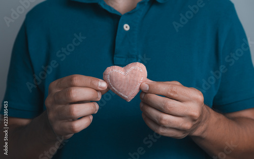 close up of a a man holding with hands a red heart cloth.