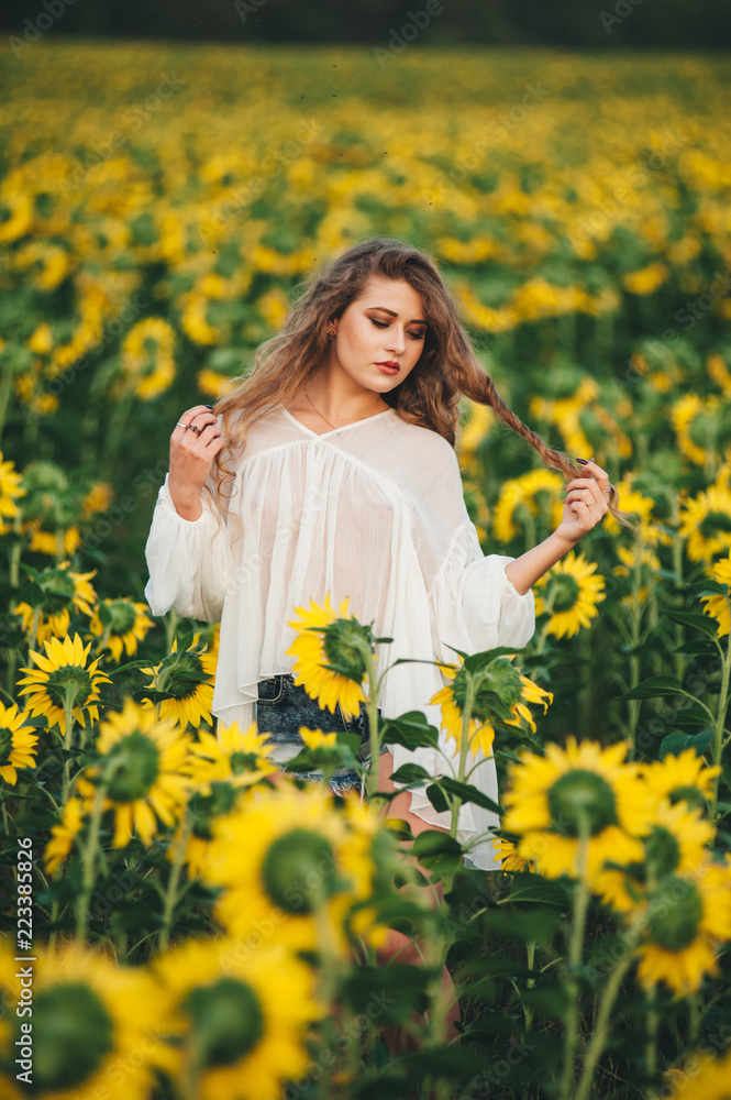 Young beautiful woman in a dress among blooming sunflowers. Agro-culture. Young beautiful woman in a dress among blooming sunflowers. Agro-culture.