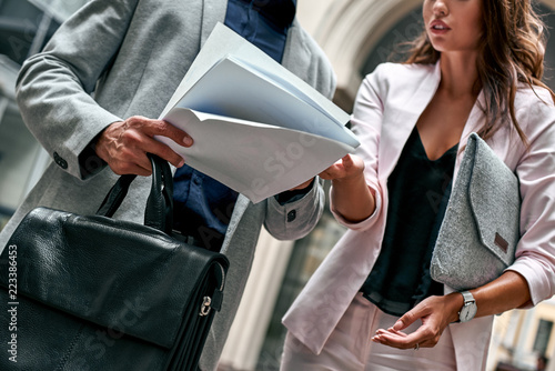 Preparation for meeting. Two young business people standing outside on the city street reading documents close-up